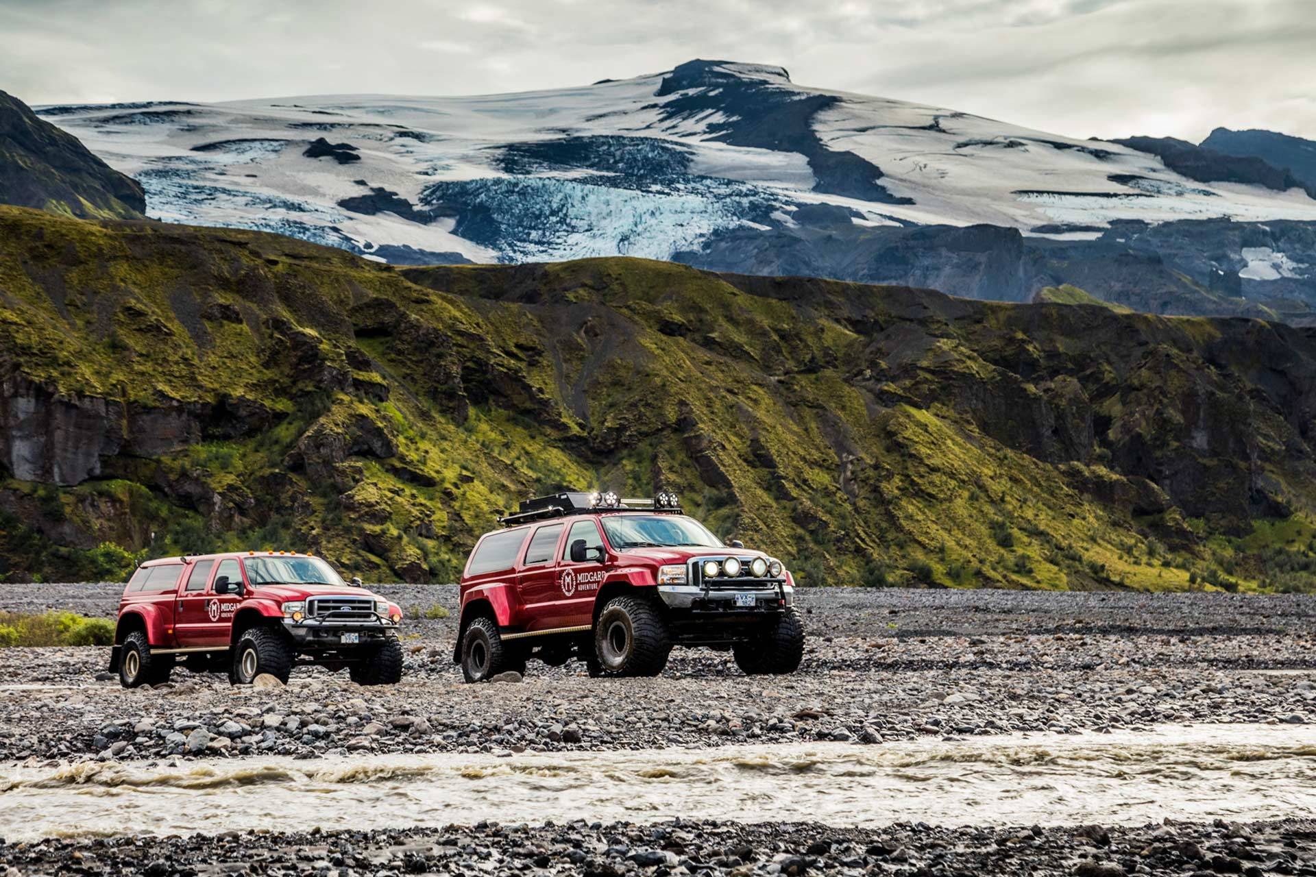 Superjeep crossing glacial river in Thorsmork highland Iceland with tourists. Surrounded by mountains and glaciers in Icelandic nature.