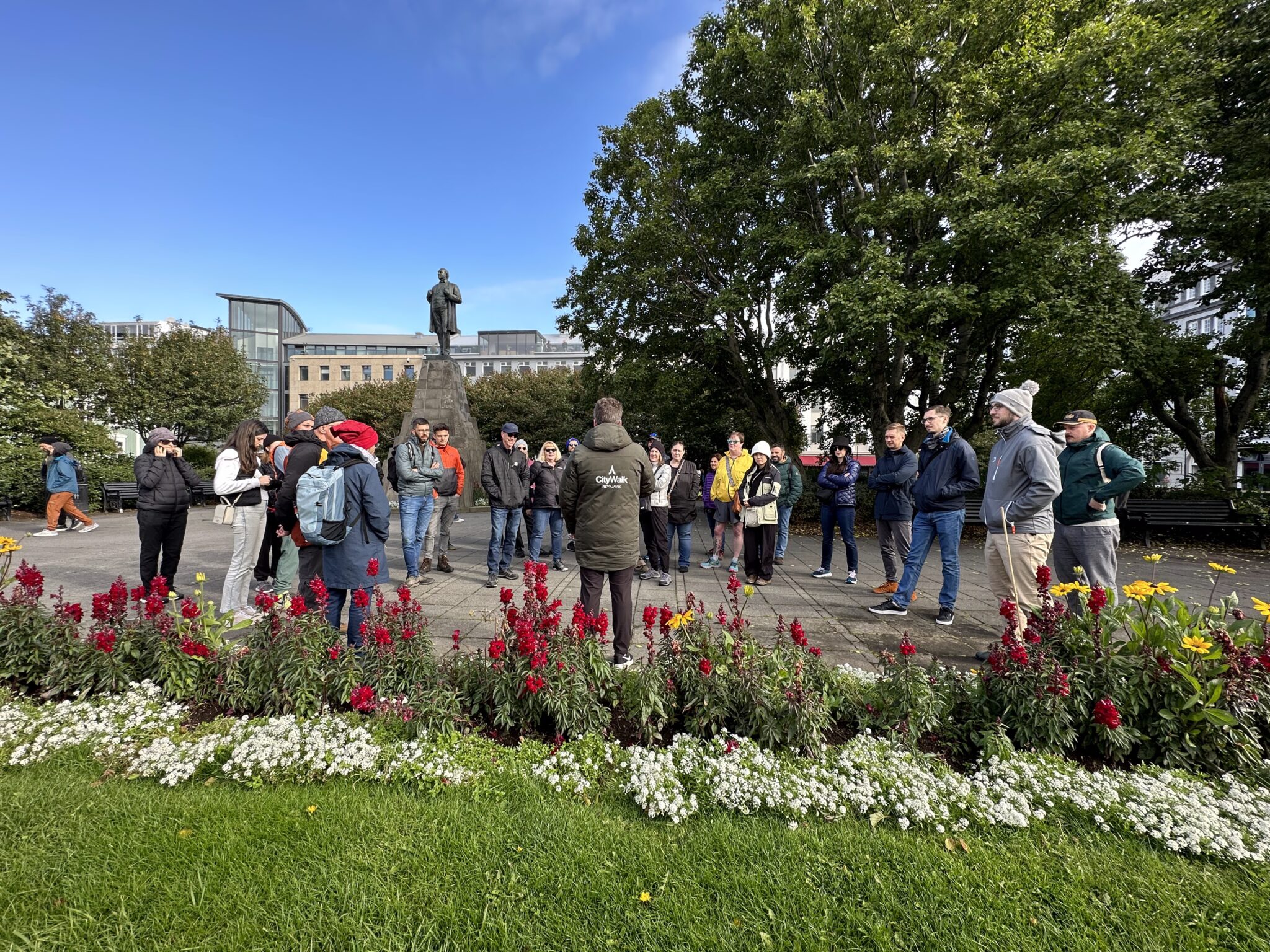 Tour guide explaining landmarks to tourists during a Free Walking Tour at Austurvöllur square in front of the parliament building.